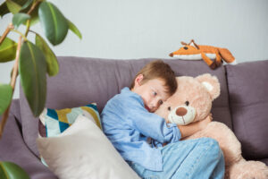 a child hugs a teddy bear on the couch in trauma therapy