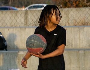 a young man holding a basketball on top of a basketball court