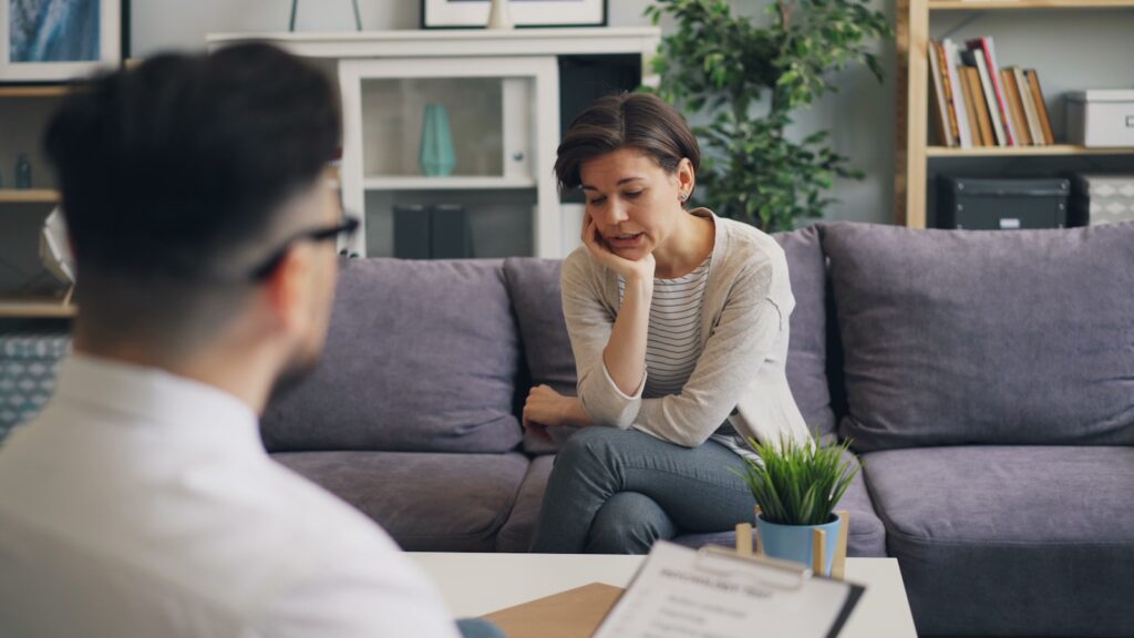 a woman sitting on a couch talking to a man