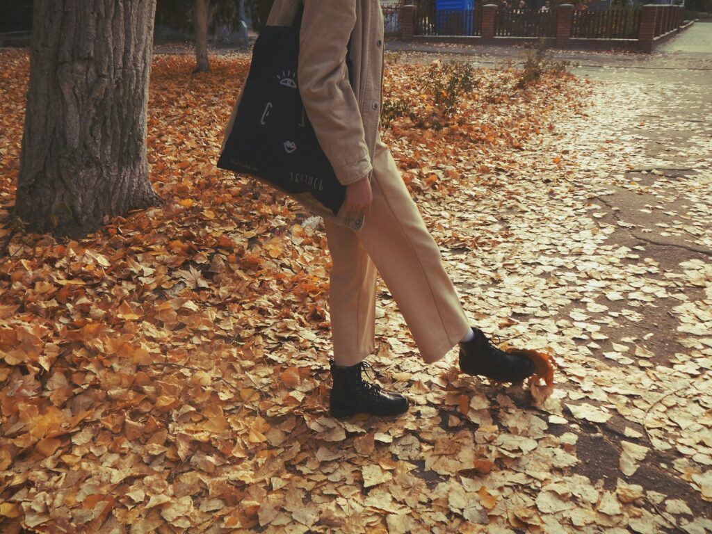 A woman walking through a leaf covered park
