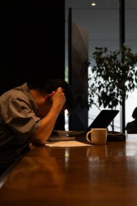 A man sitting at a table with his head in his hands