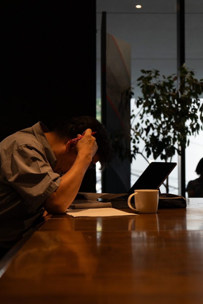 A man sitting at a table with his head in his hands